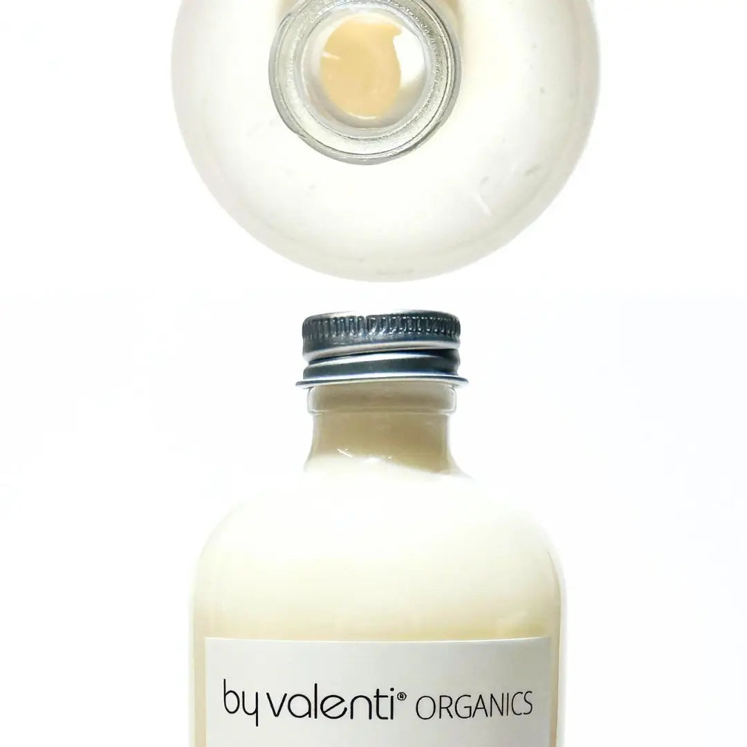 Bottle of by valenti Organics body lotion with a close-up of the cap on a white background