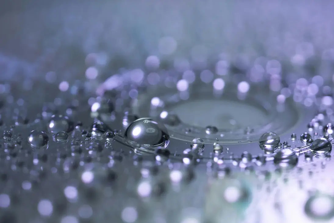 Close-up of water droplets on a reflective surface with a blurred background